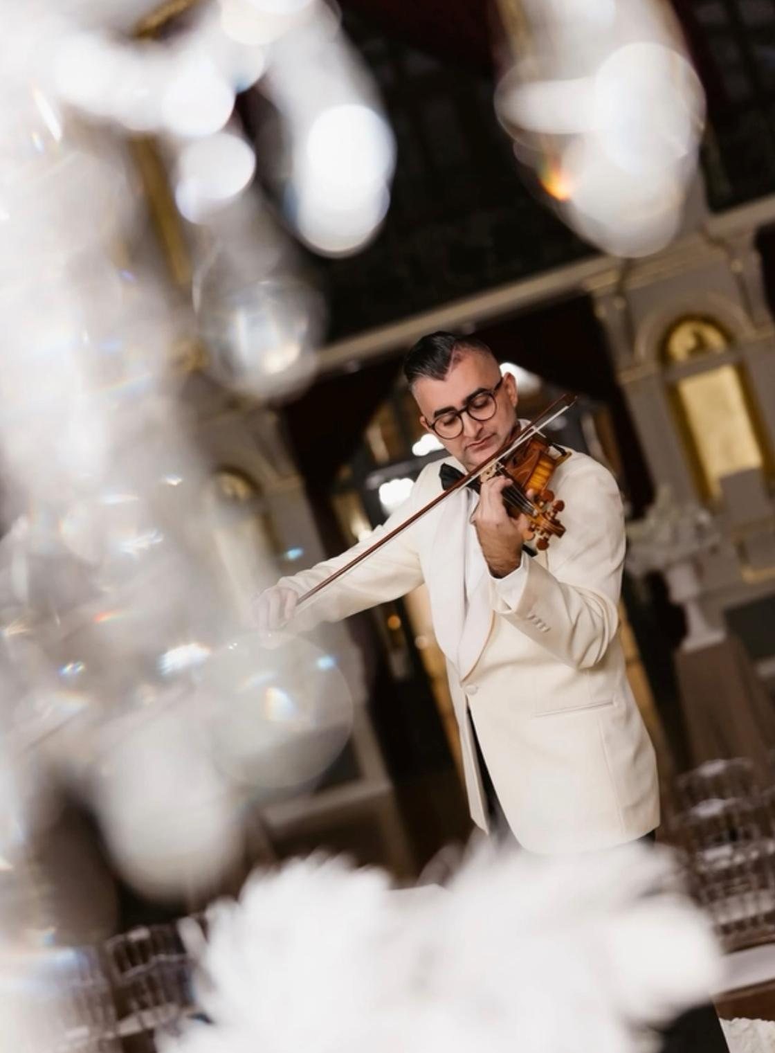 Ion Scripcaru in a white jacket playing the violin